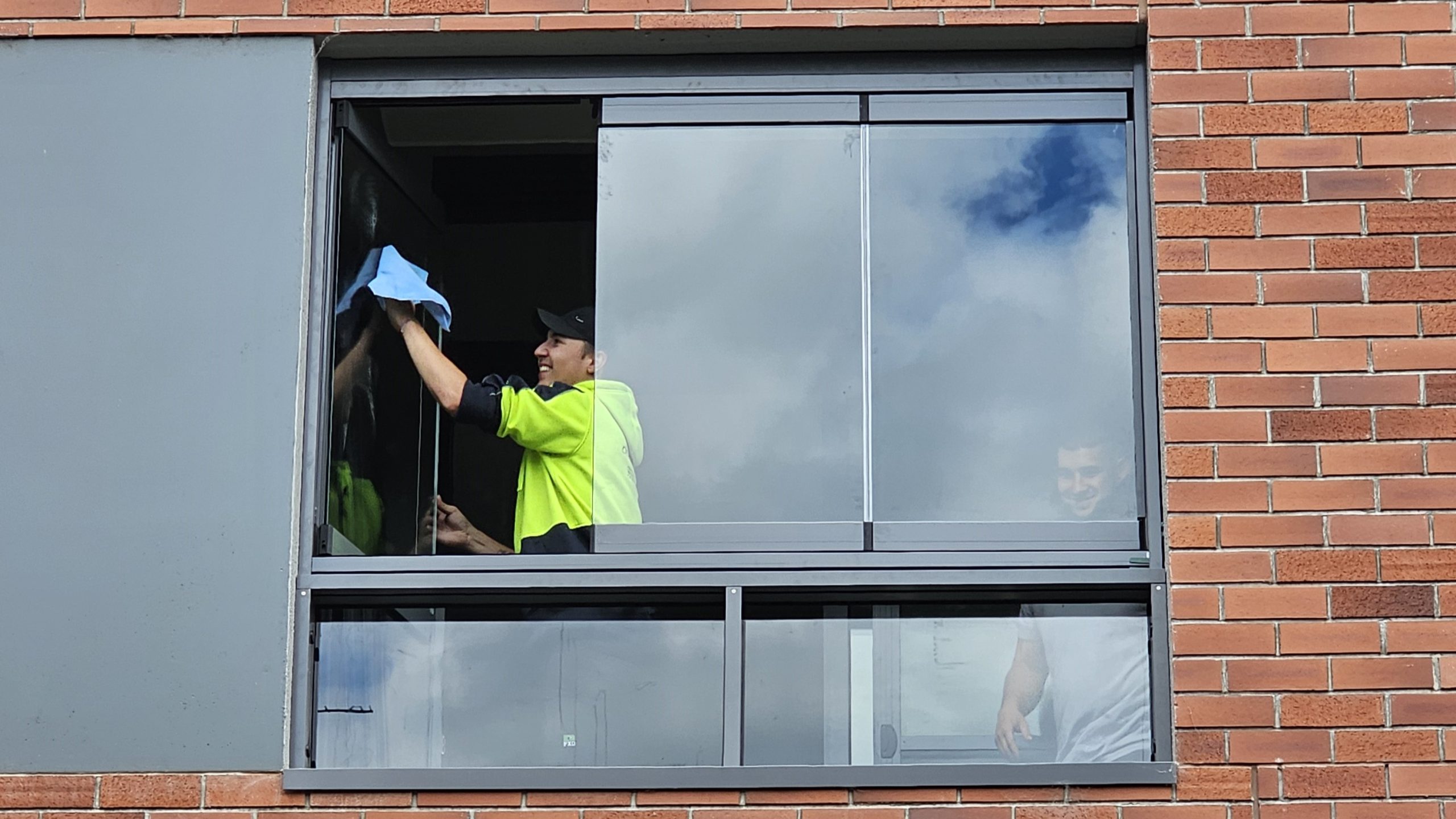 Man cleaning a glass panel on balcony